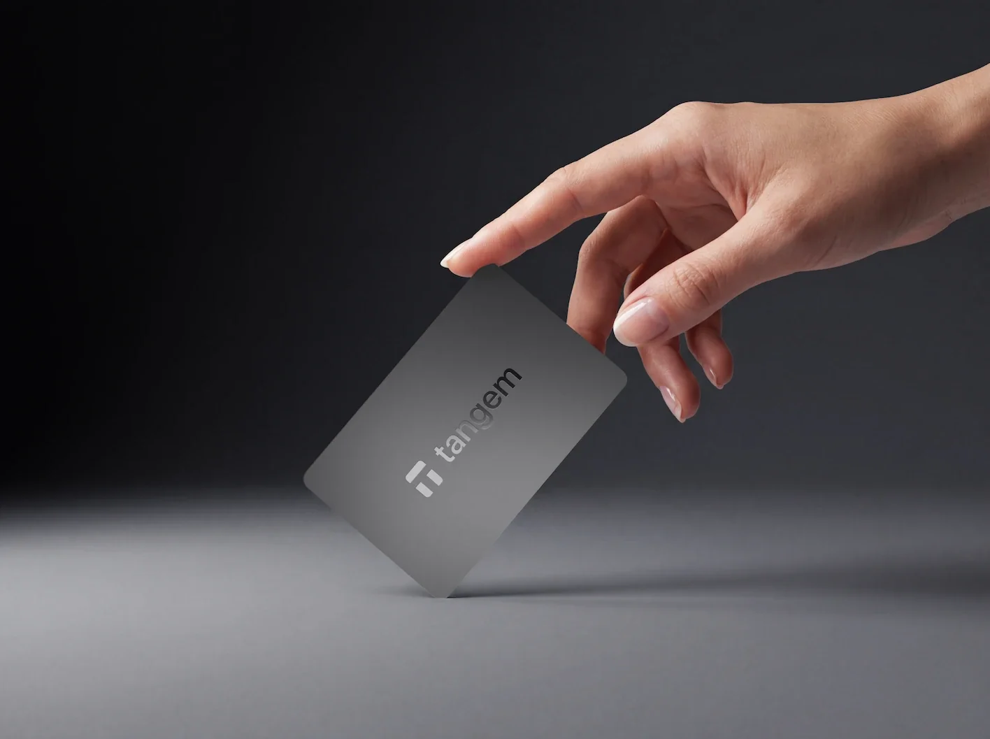Tangem Wallet card held between two fingers