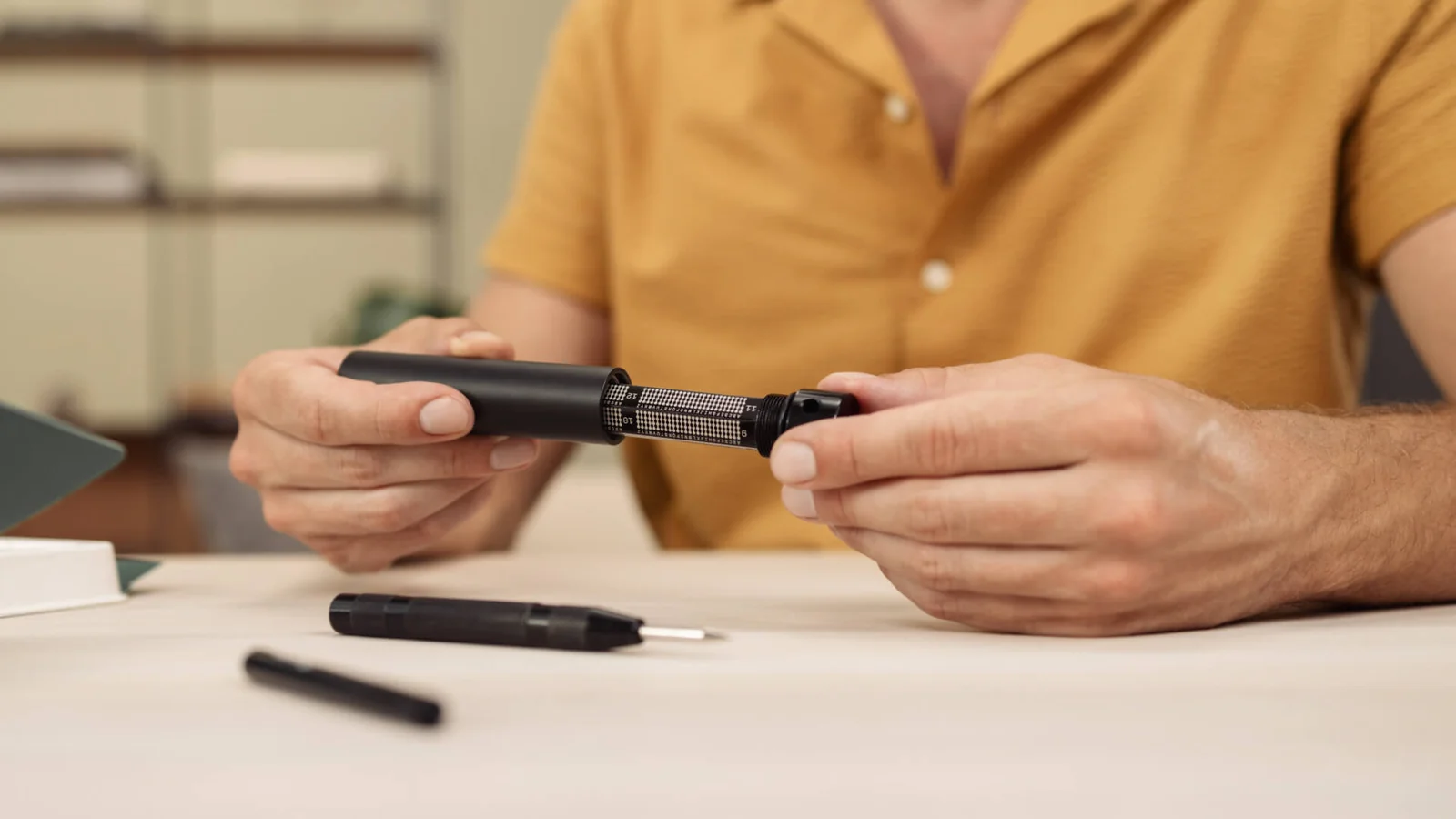 Trezor Keep Metal steel seed phrase backup capsule being opened, with its punch tool on the desk