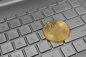 A bitcoin coin resting on a laptop keyboard, illustrating wallets used for airdrop farming