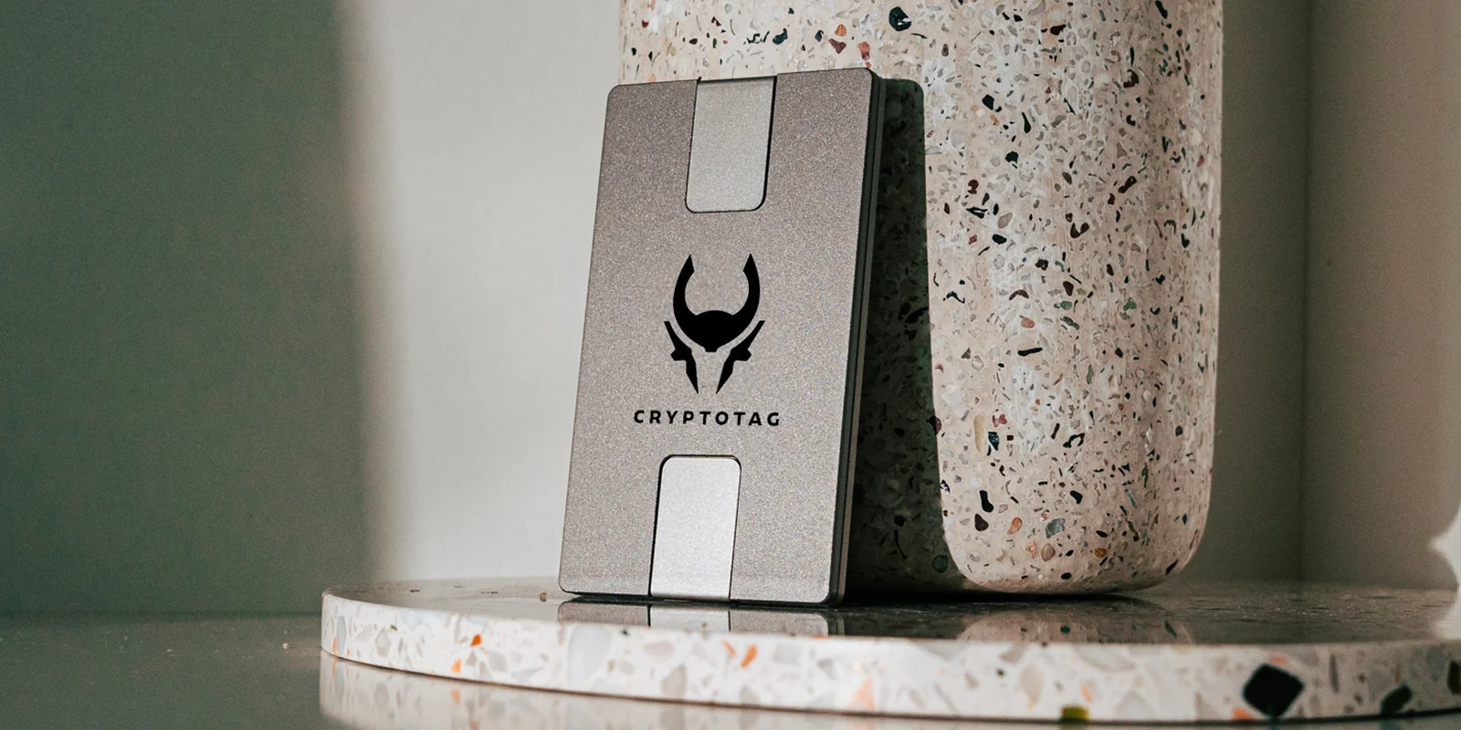 Cryptotag Zeus titanium seed phrase plate standing against a terrazzo surface