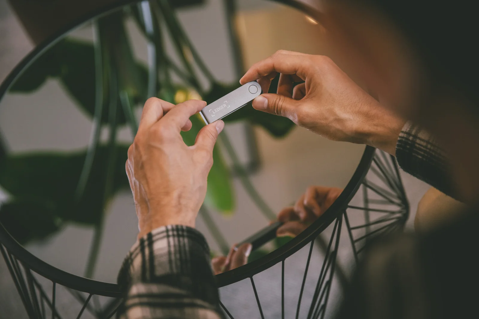 Two hands holding a Ledger Nano X hardware wallet before plugging it into a computer to connect it to MetaMask