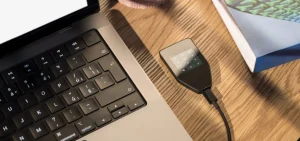 Trezor Safe 5 hardware wallet connected to a laptop by USB-C, showing the PIN pad on its touchscreen before connecting to MetaMask