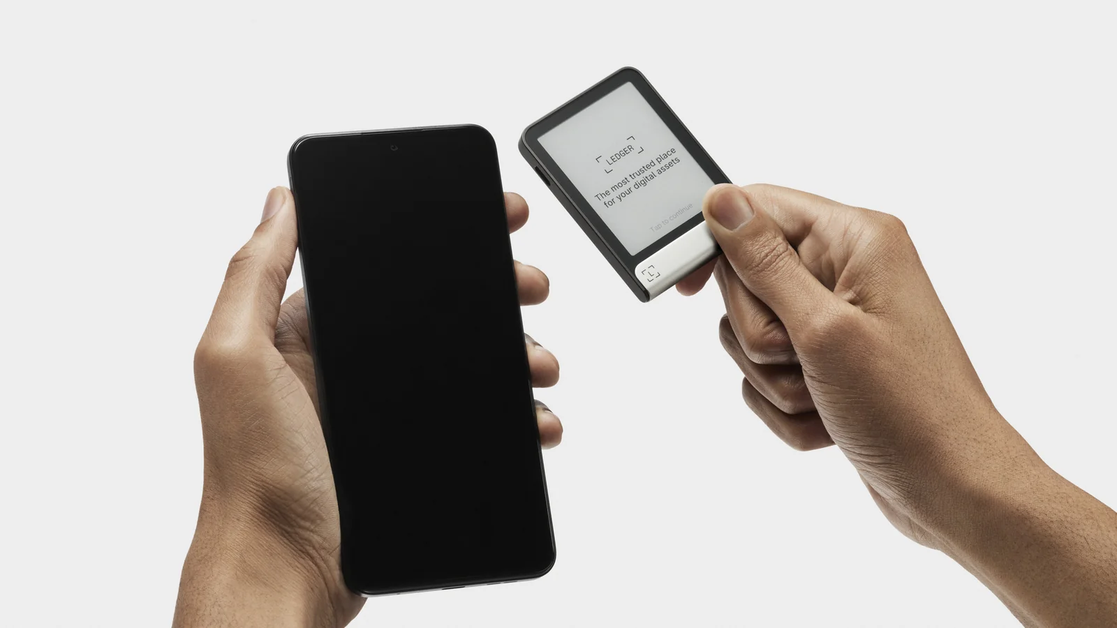 A person holding a Ledger Flex hardware wallet in one hand and a smartphone in the other during setup