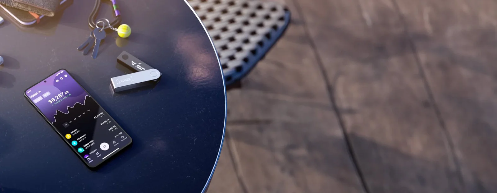 Ledger Nano X lying on a table beside a phone running the Ledger Wallet app over Bluetooth