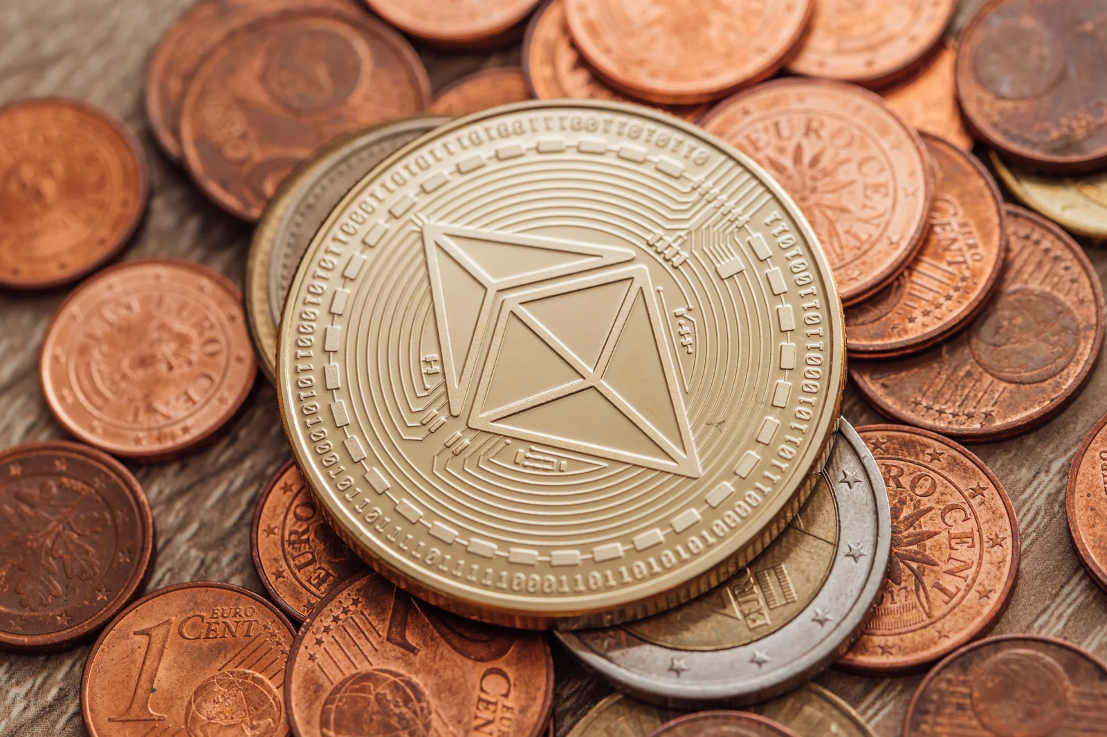 Physical Ethereum coin resting on loose euro cents, illustrating the Ethereum side of the Solana vs Ethereum comparison