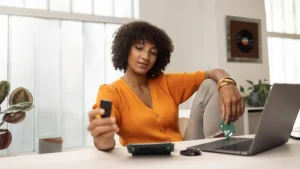 Person holding a Trezor Safe 3 hardware wallet at a desk with a laptop and a wallet backup card