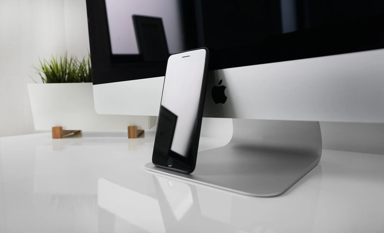 Smartphone standing on a white desk in front of a monitor, the setup you use Trust Wallet and Coinbase Wallet on