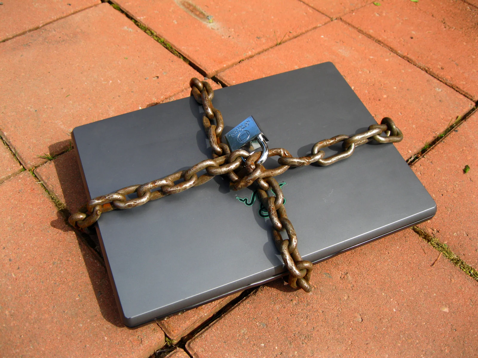 A laptop wrapped in a chain and padlock, a reminder to clean or wipe the computer after a crypto wallet hack